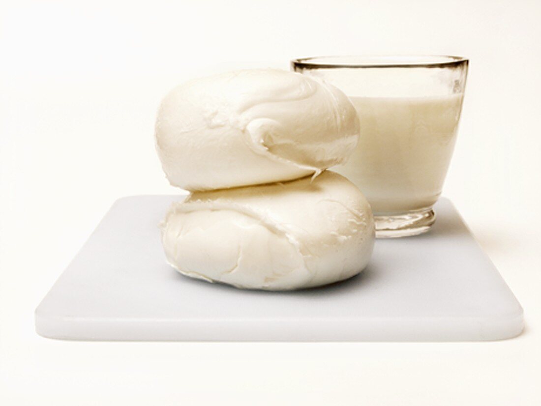 Mozzarella und Glas Milch auf Schneidebrett