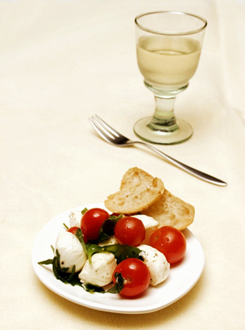 Mozzarella mit Tomaten und Basilikum; Glas Weißwein