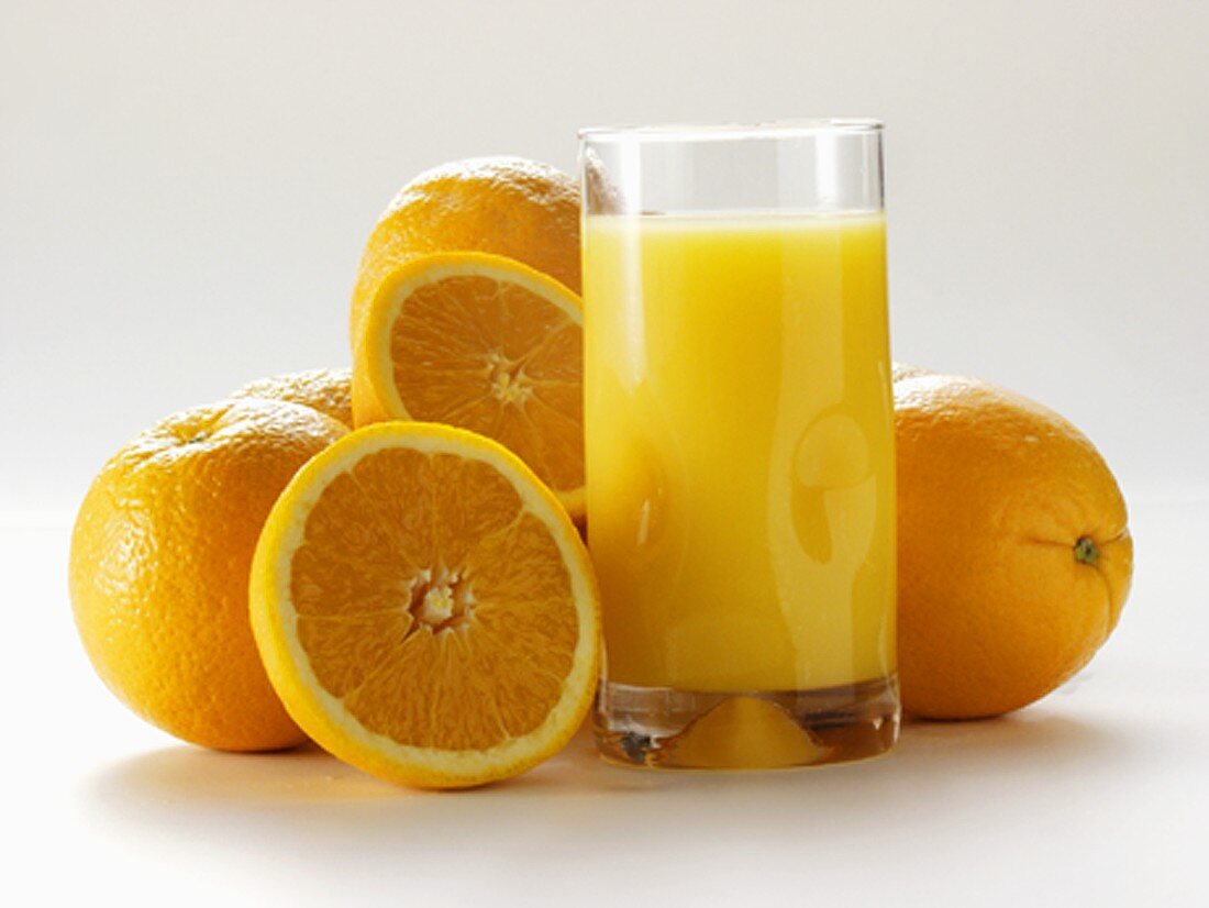 Glas Orangensaft und frische Orangen