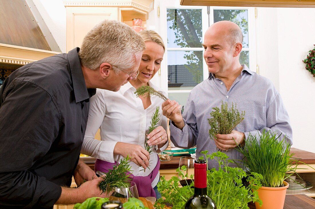 Kitchen scene: a woman and two men examining fresh herbs