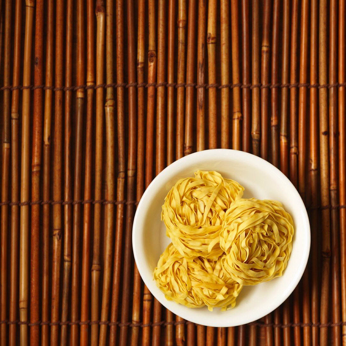 Chinese egg noodles in a dish on a bamboo mat
