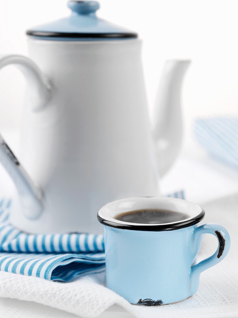 A mug of coffee and a coffee pot