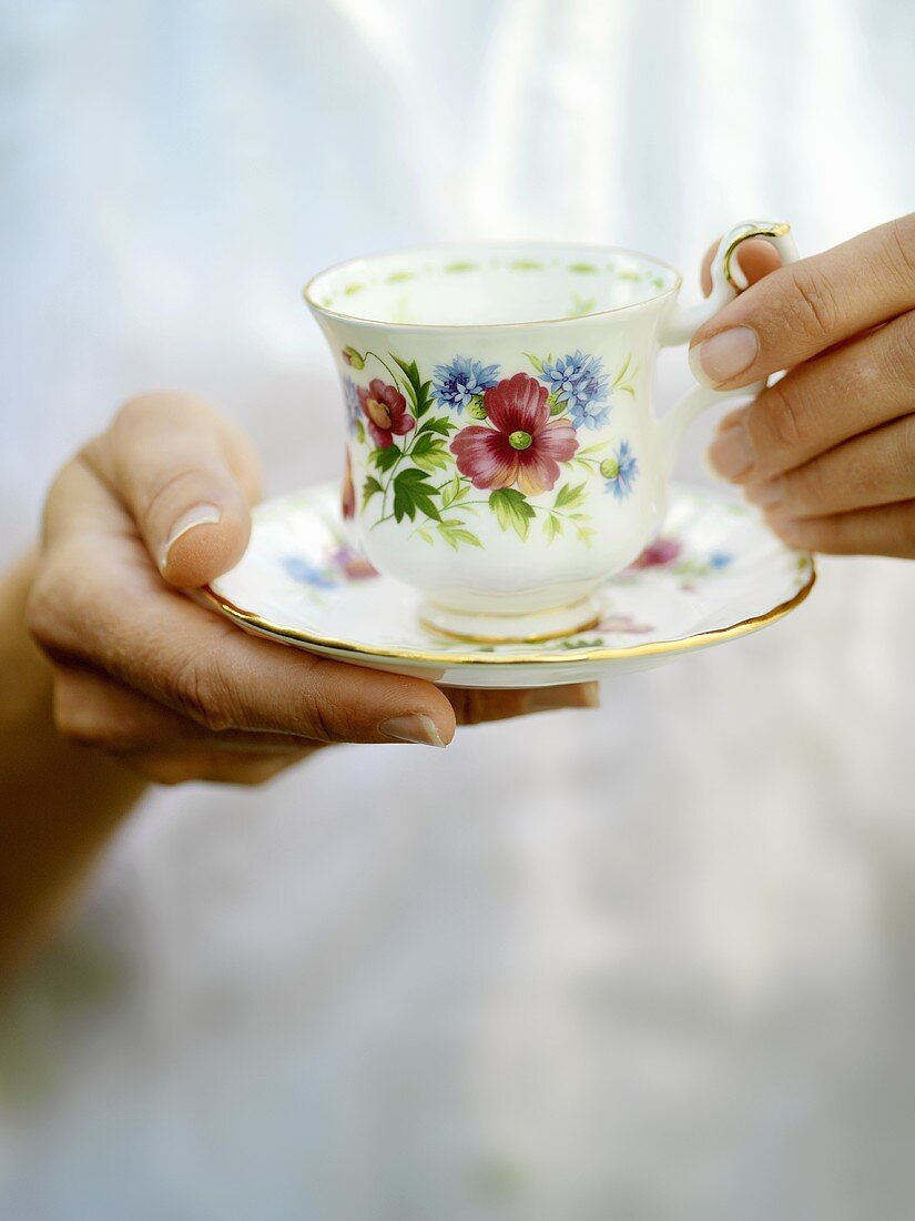 Hands holding a cup and saucer