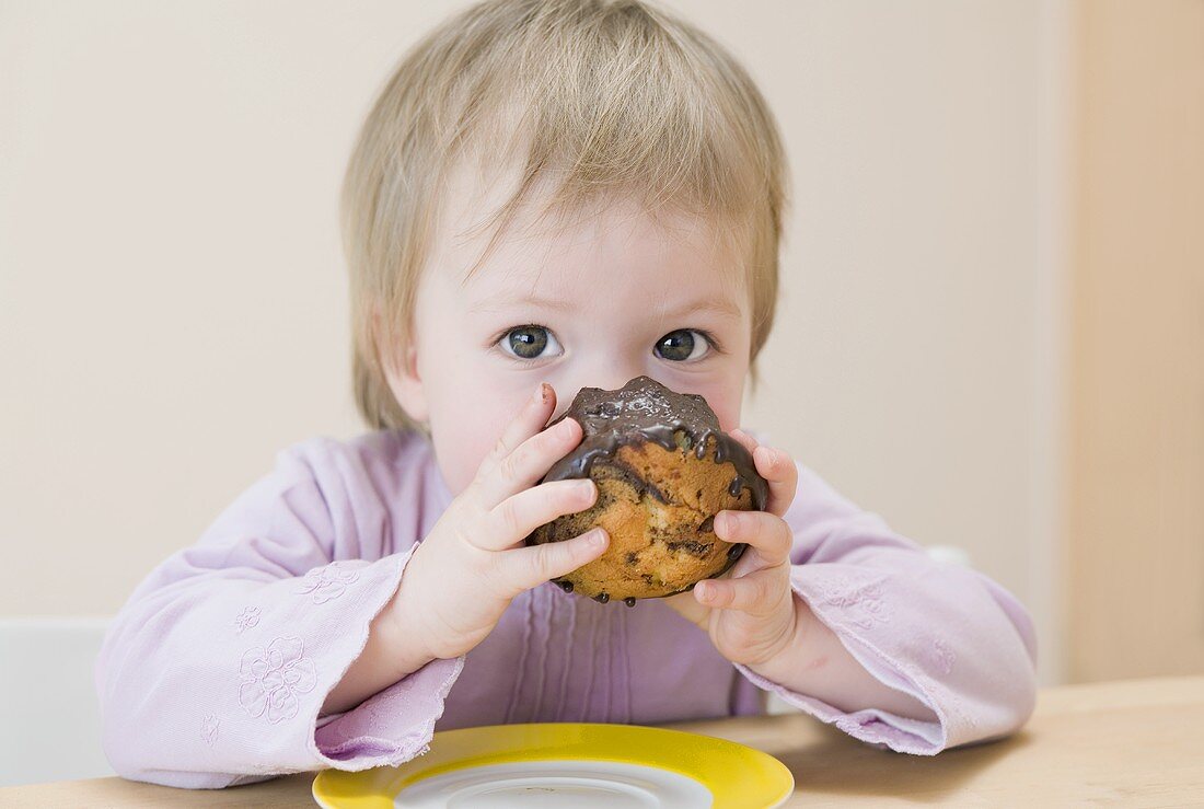 Small girl biting into a chocolate gugelhupf