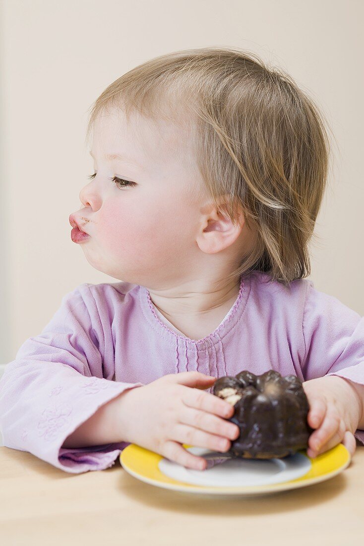 Small girl with a chocolate gugelhupf (with a bite taken)
