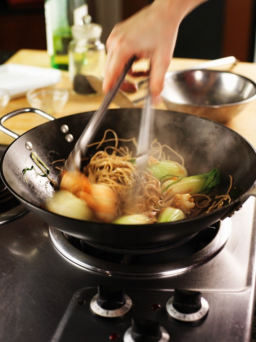 Cooking soba noodles and vegetables in a wok