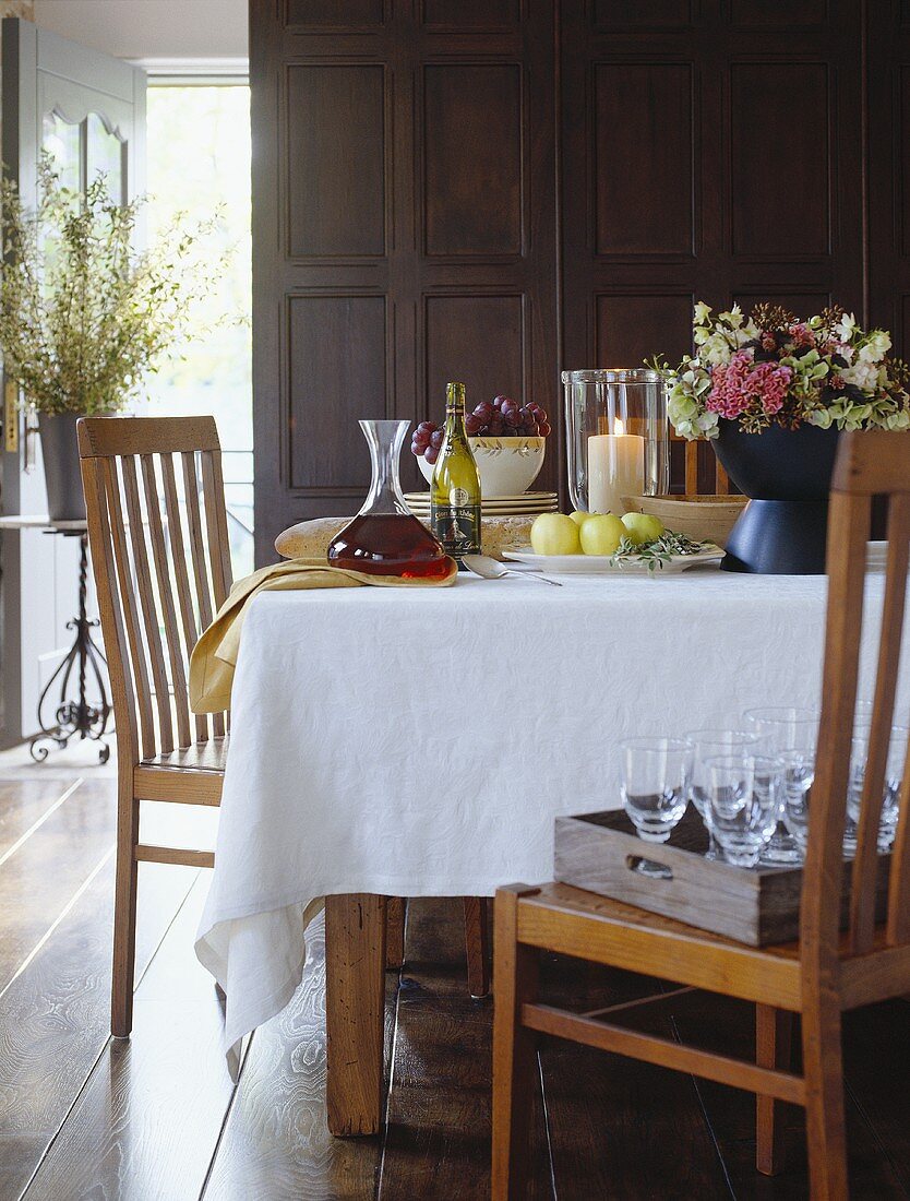 Gedeckter Tisch mit Wein, Weintrauben, Blumen und Äpfeln