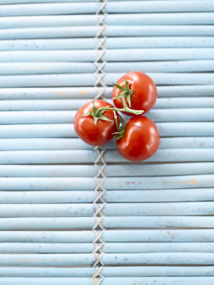 Three tomatoes on blue mat