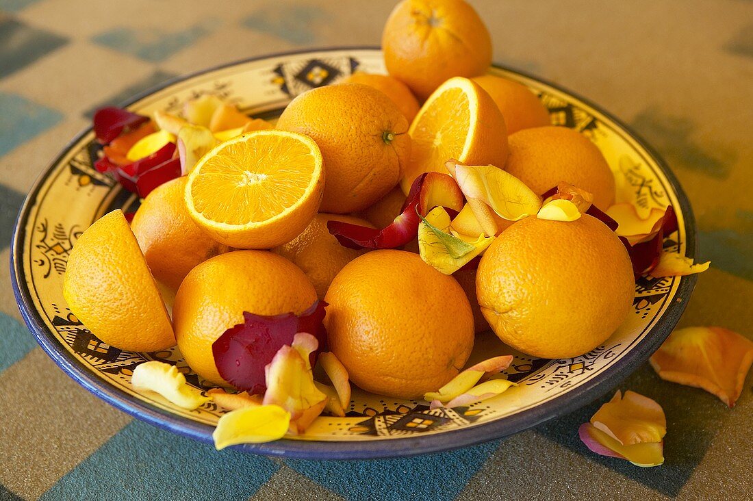 Orangen mit Rosenblättern in einer Schale