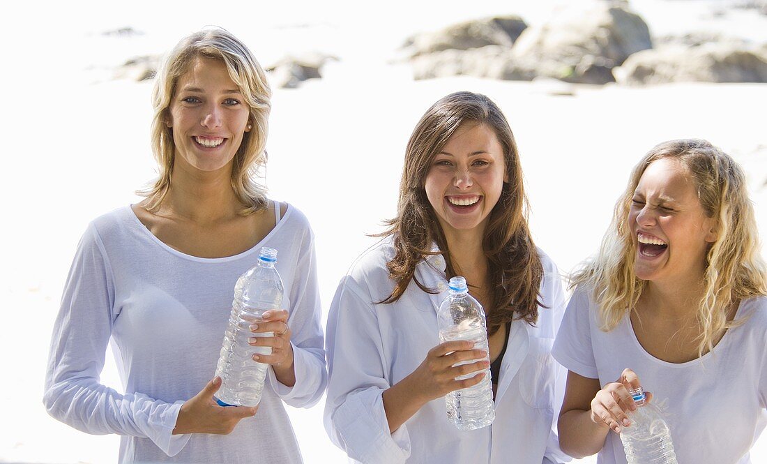 Three girls with bottles of water on the beach