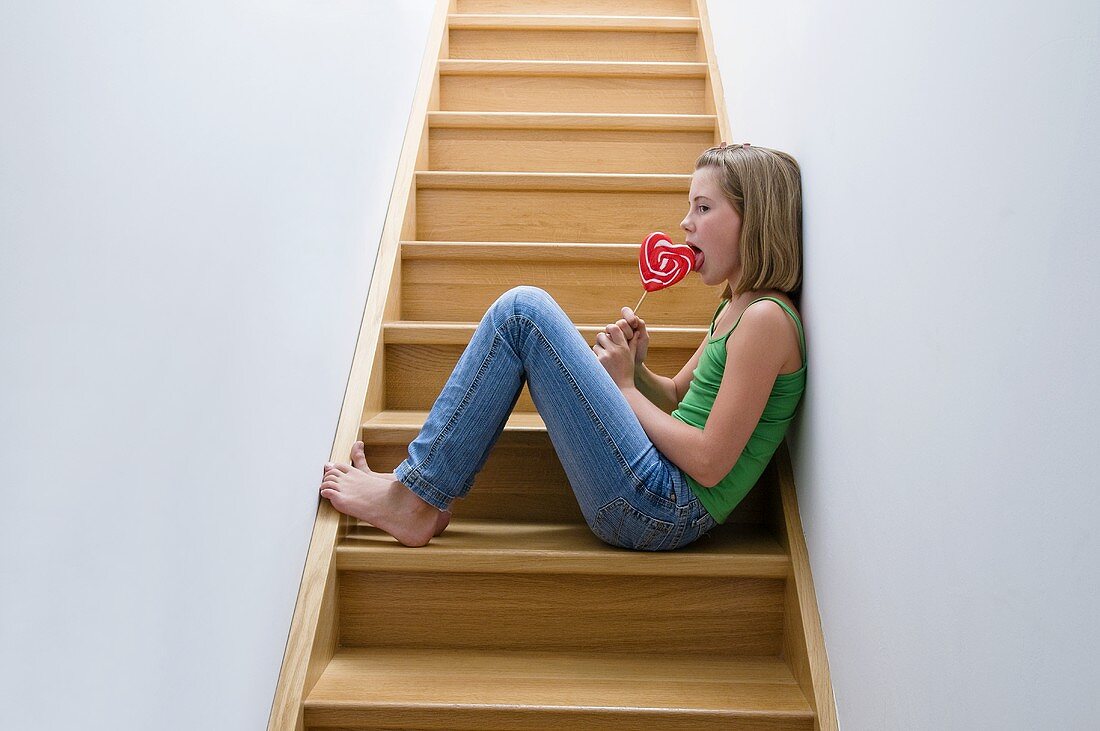 Mädchen mit Lutscher sitzt auf der Treppe