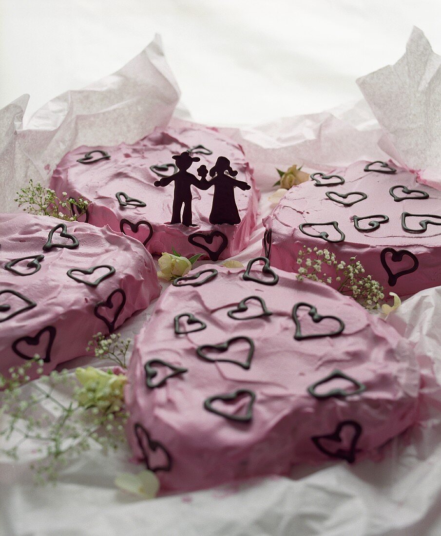 Pink cake with chocolate hearts and bridal couple