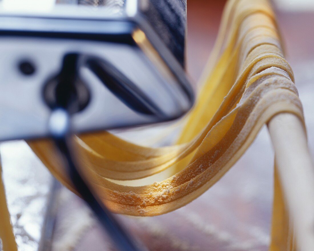 Homemade tagliatelle coming out of a pasta machine