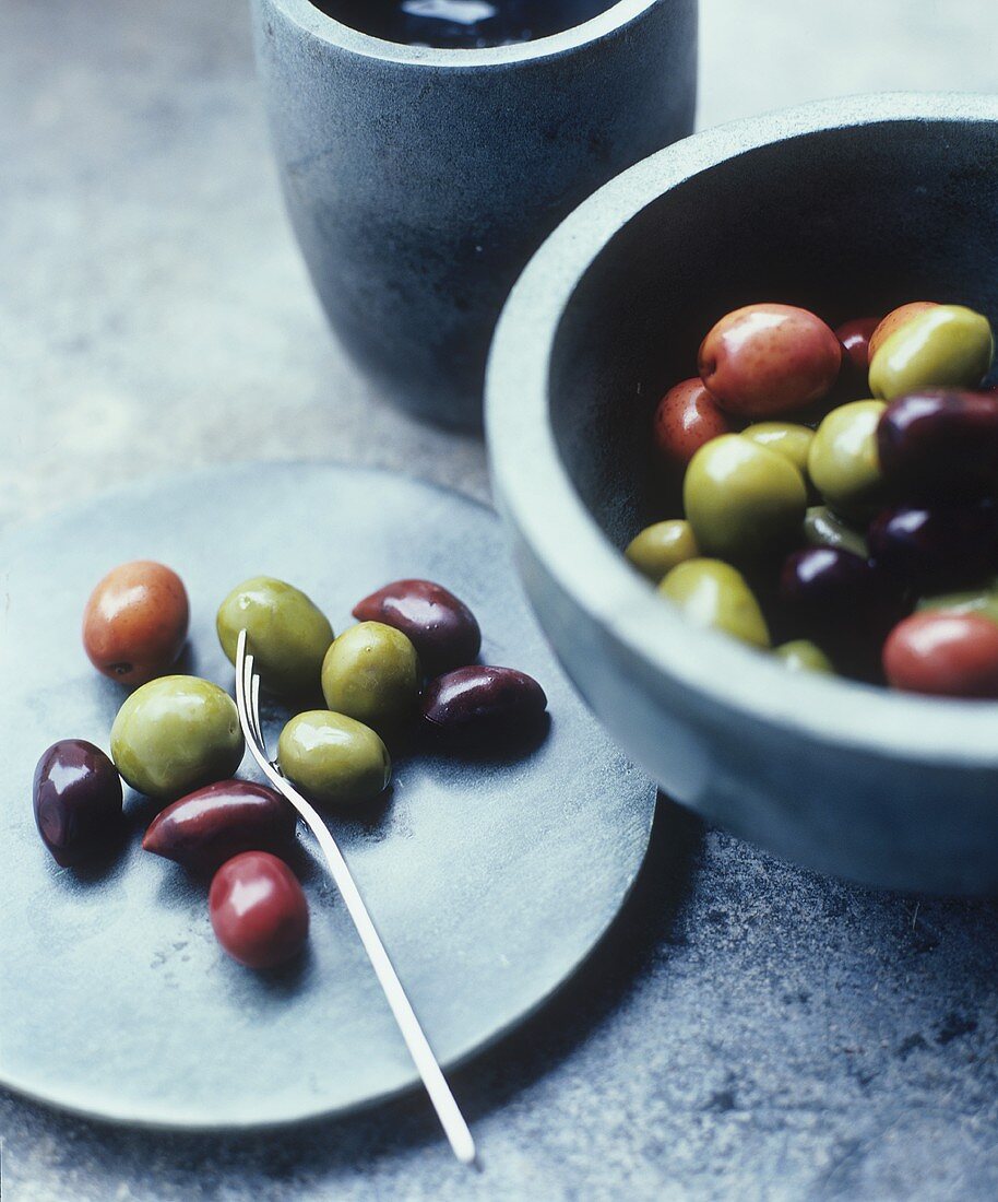 Green, red and black olives on plate and in bowl