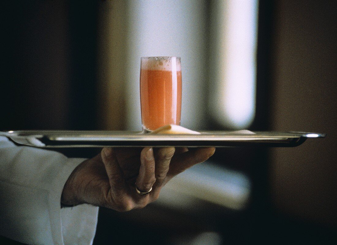A Champagne-Peach Drink being served by a waiter