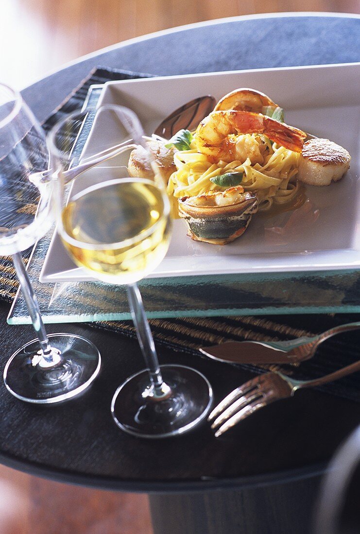 Linguine with seafood on plate and a glass of wine