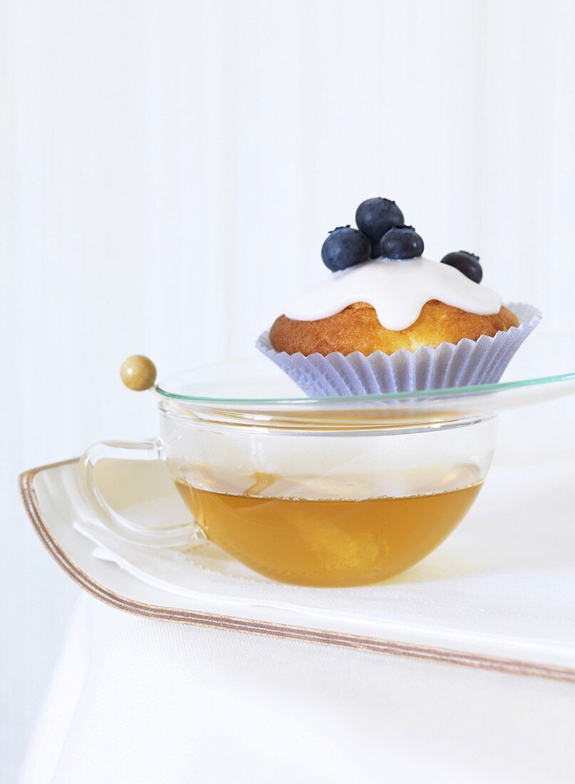 A blueberry muffin on a cup of tea