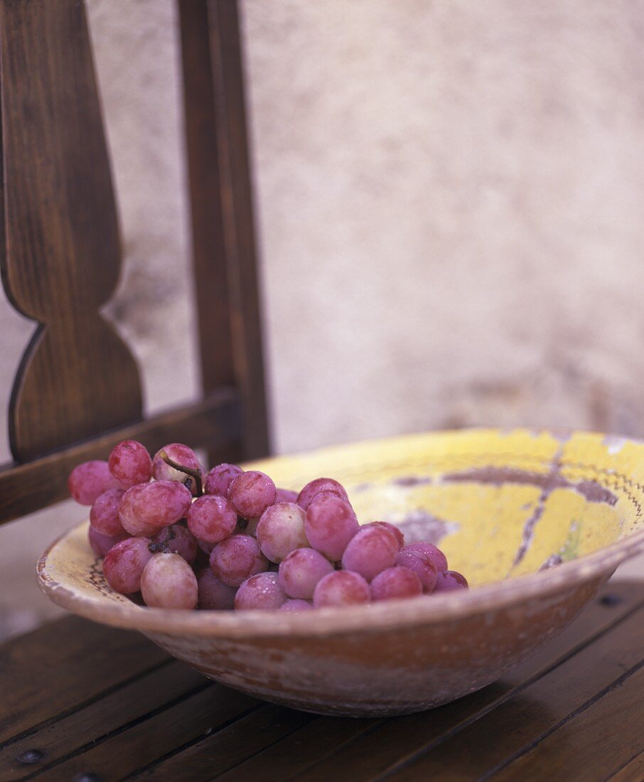 Teller mit roten Trauben auf einem Holzstuhl