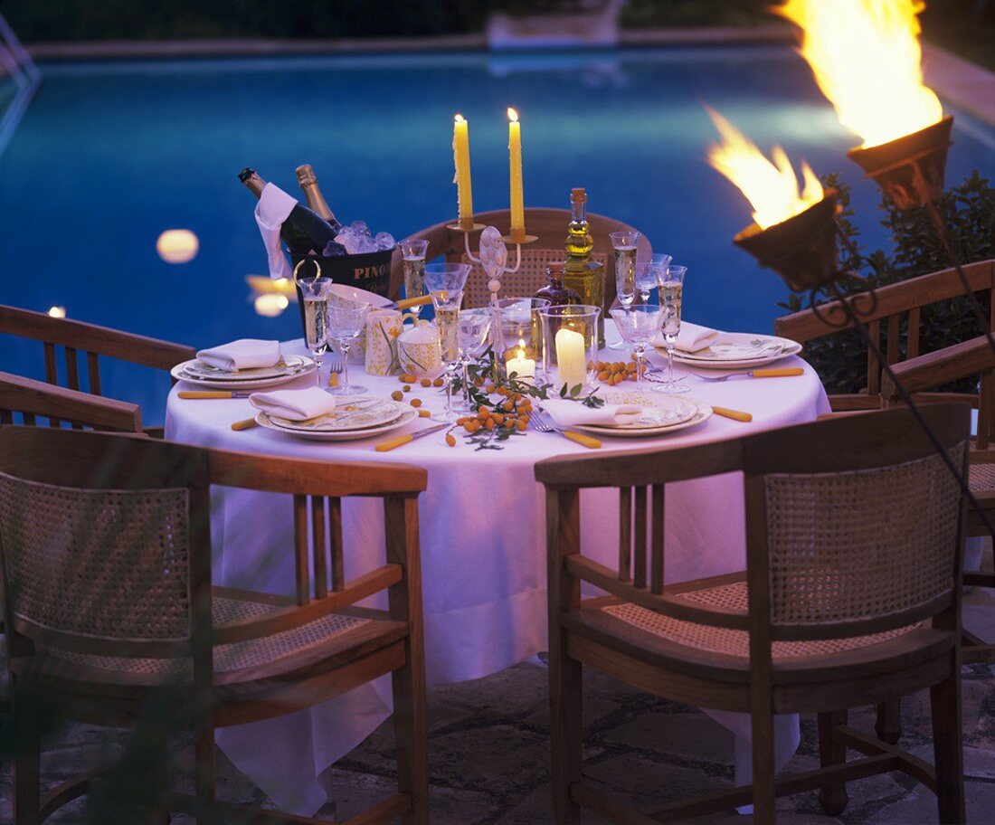 Table laid for special occasion by pool, evening atmosphere