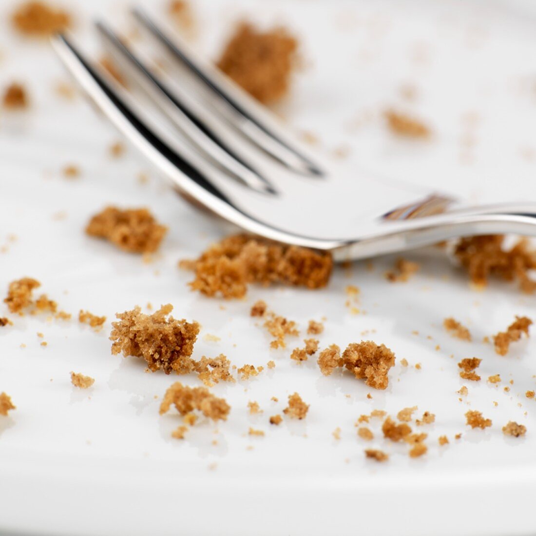 A cake fork surrounded by cake crumbs