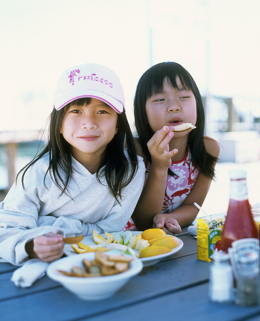 Zwei Mädchen essen Obstschnitze