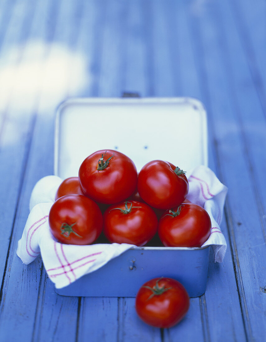 Tomatoes and tea towel in a metal box