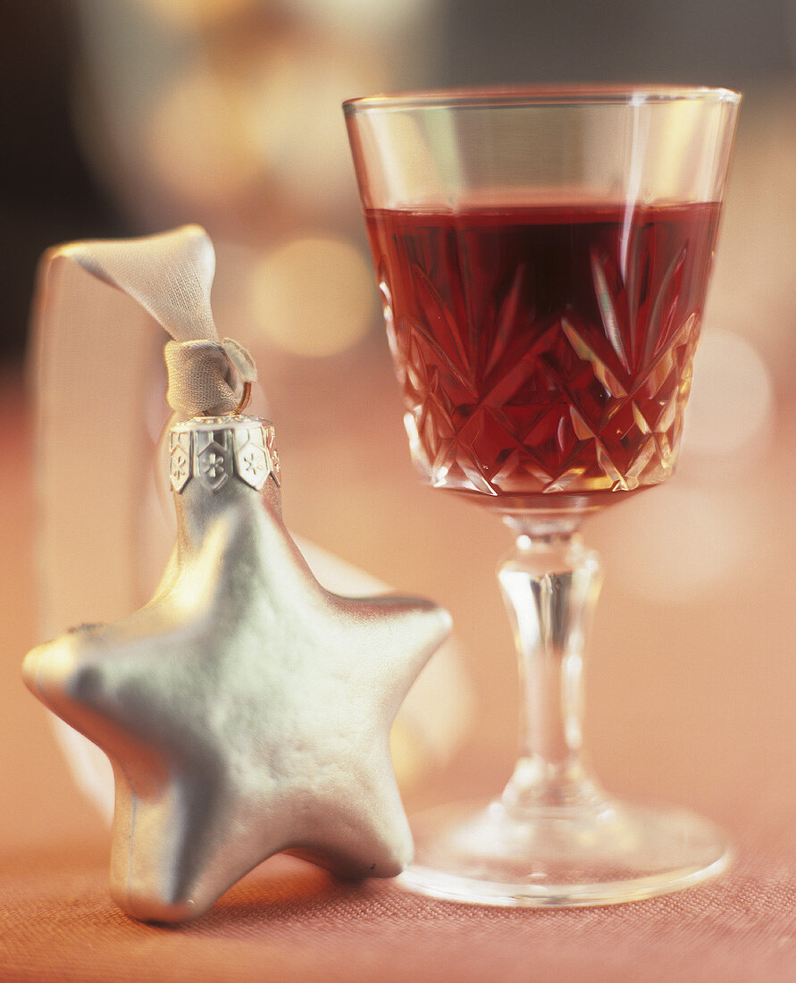 A glass of red wine with a Christmas decoration