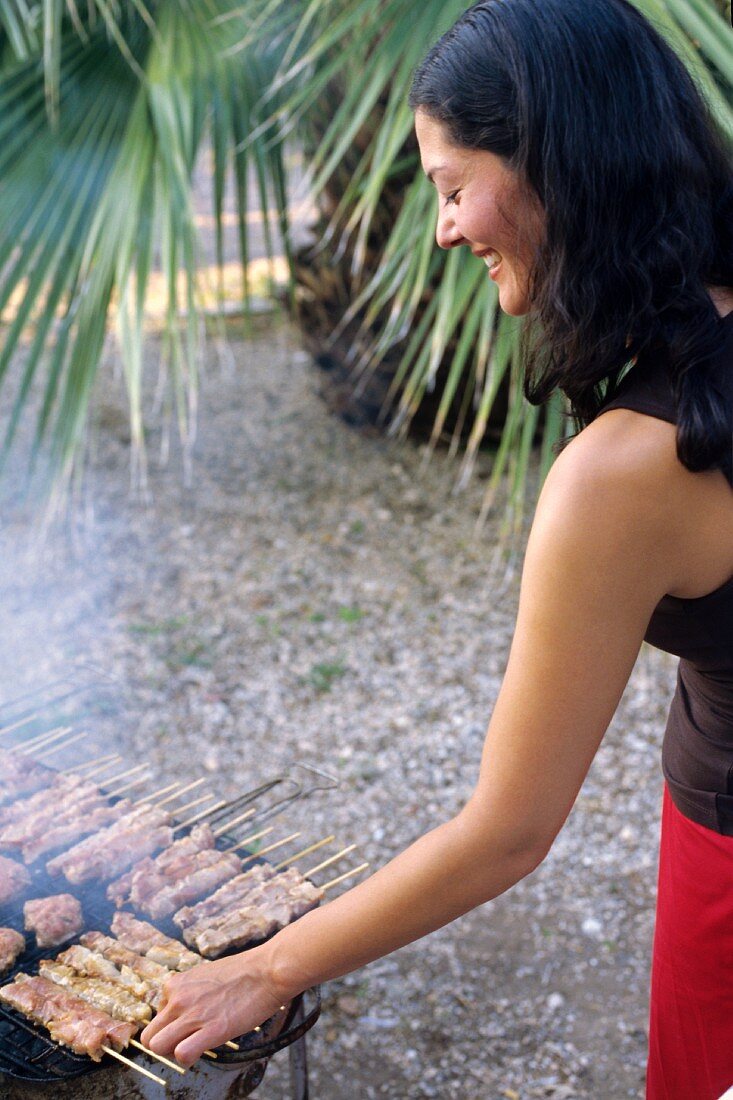 Junge Frau beim Grillen unter Palmen