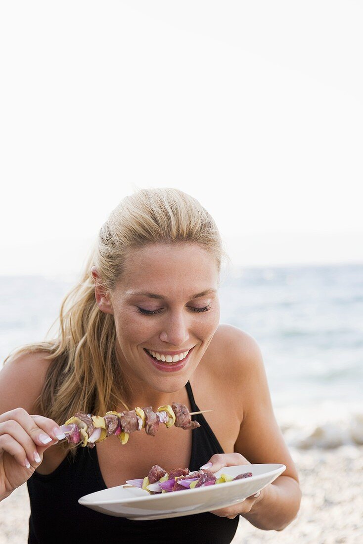 Blond woman eating shashlik