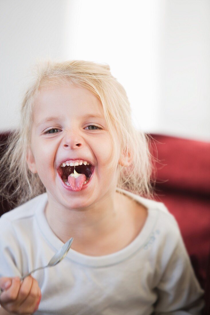 Blondes Mädchen mit Joghurt auf der Zunge