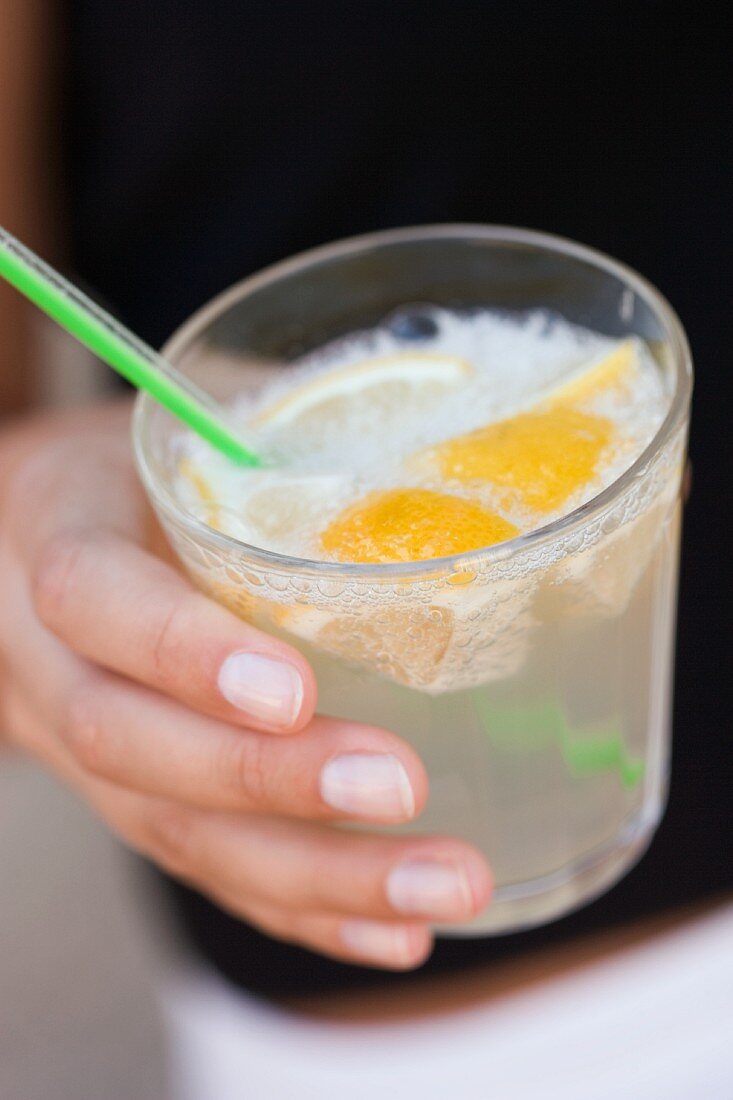 Hand holding a glass of lemonade