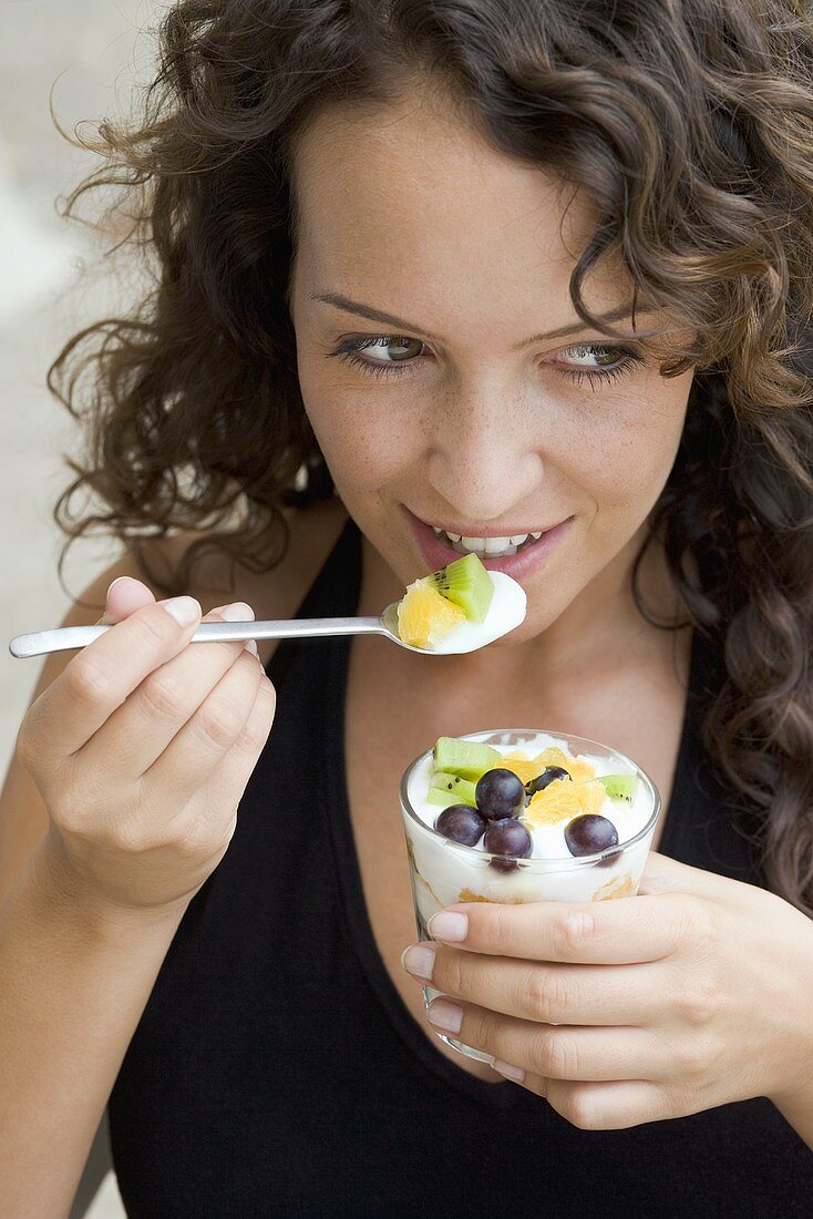 Frau isst Joghurt mit frischen Früchten