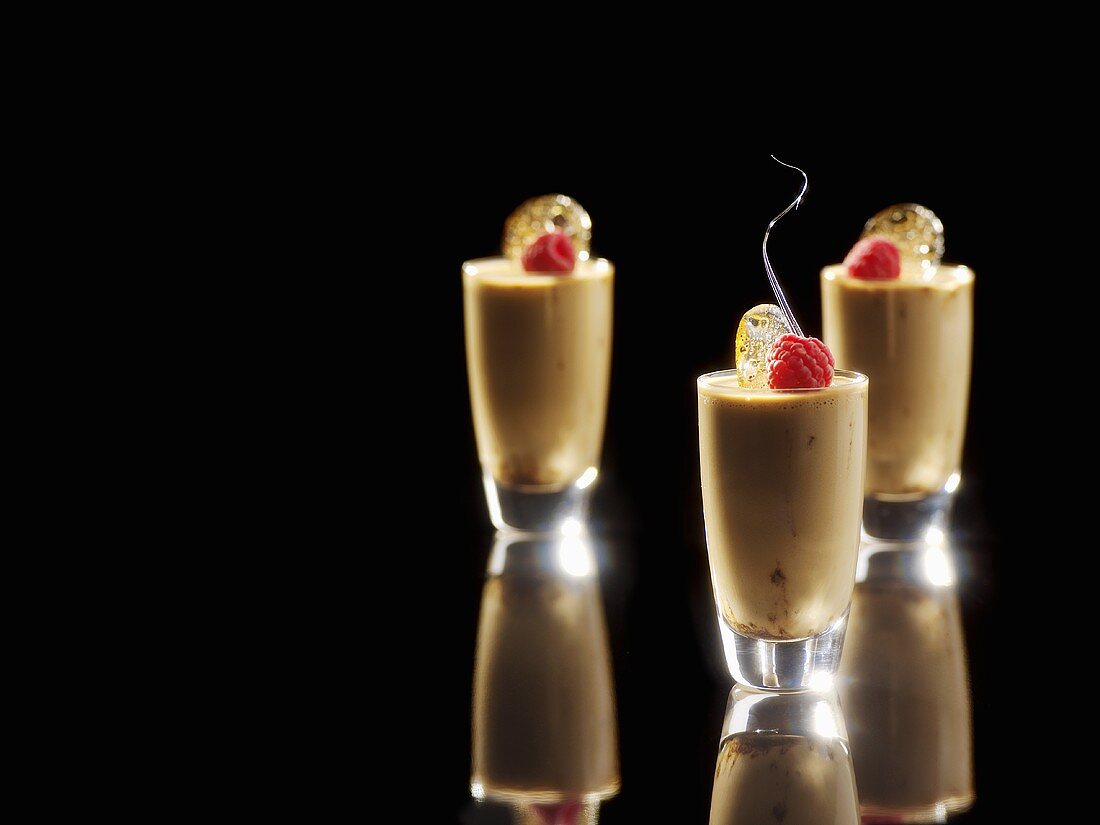 Liquorice panna cotta in three glasses decorated with raspberries