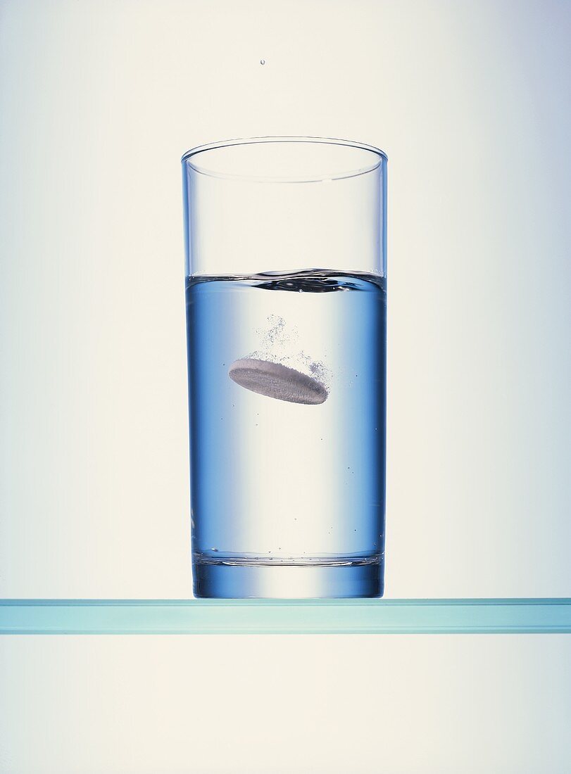 Brausetablette fällt in ein Glas Wasser