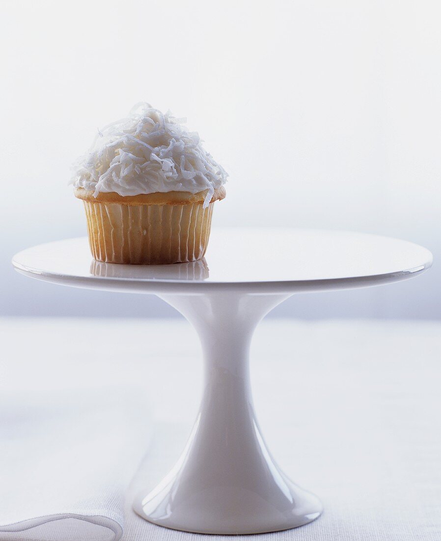 A coconut cupcake on a cake stand