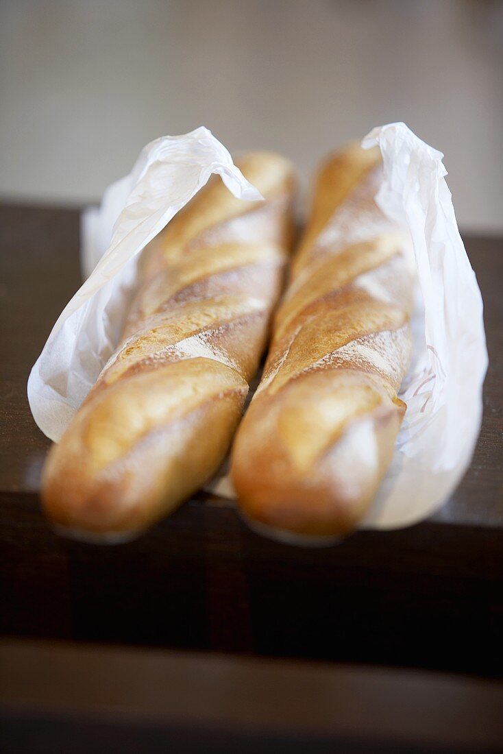 Two baguettes wrapped in paper