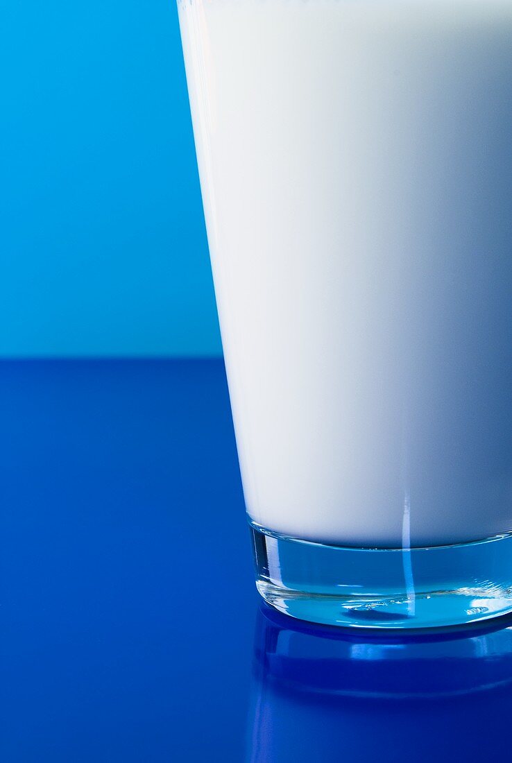 Ein Glas Milch vor blauem Hintergrund