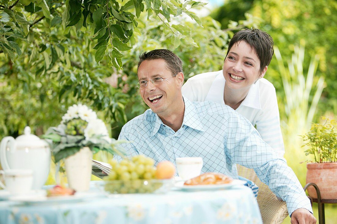 Young couple at laid breakfast table in garden