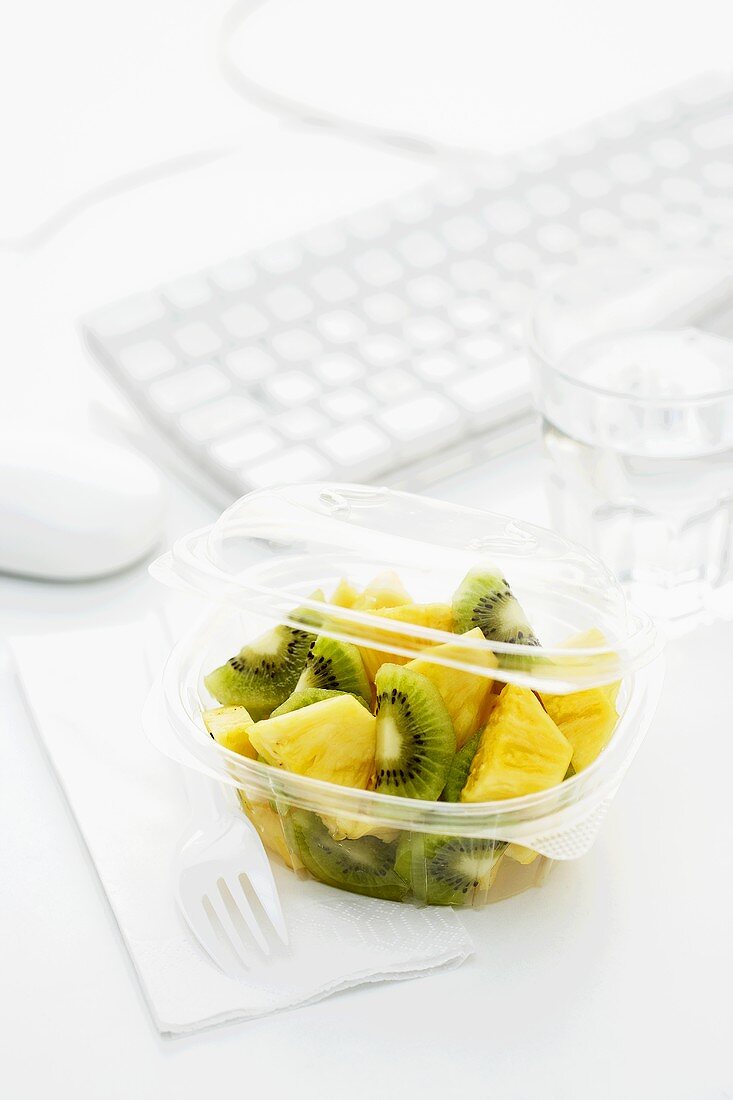 Kiwi fruit and pineapple salad in plastic container