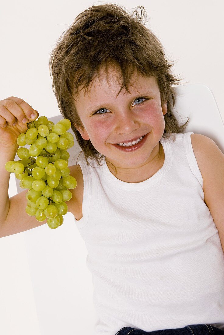 Small boy with a bunch of grapes in his hand