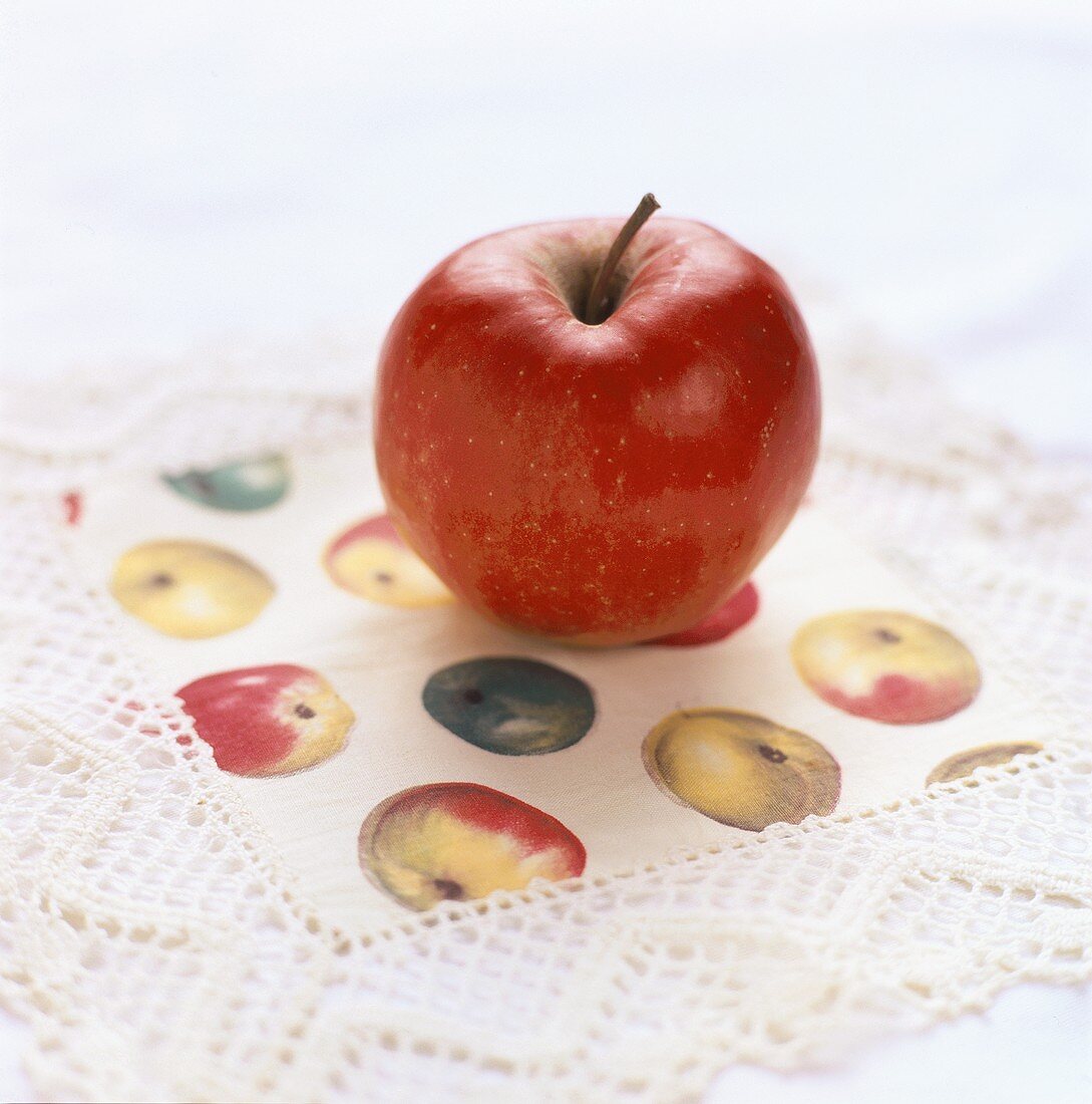 An apple on a doily with apple design