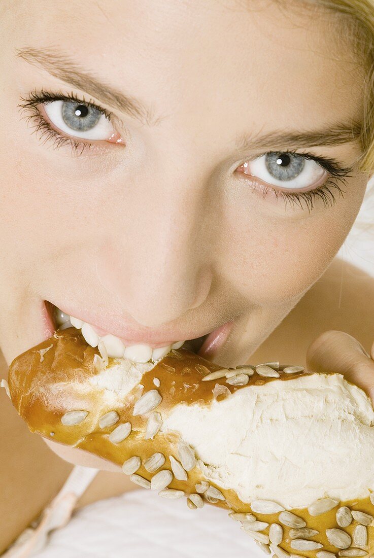 Woman eating pretzel stick with sunflower seeds