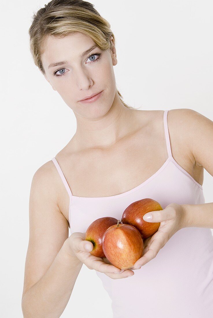 Junge Frau hält drei Äpfel in den Händen