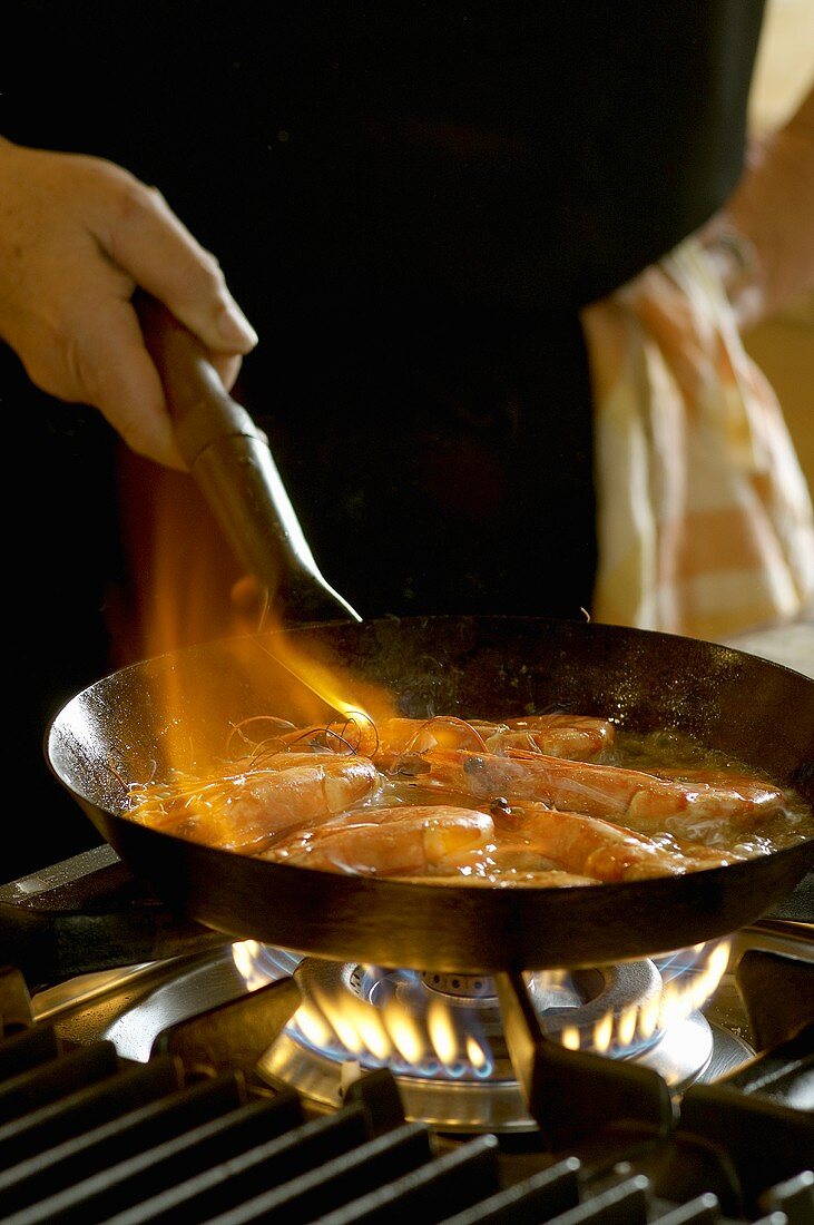 Flambéing lemon and garlic prawns