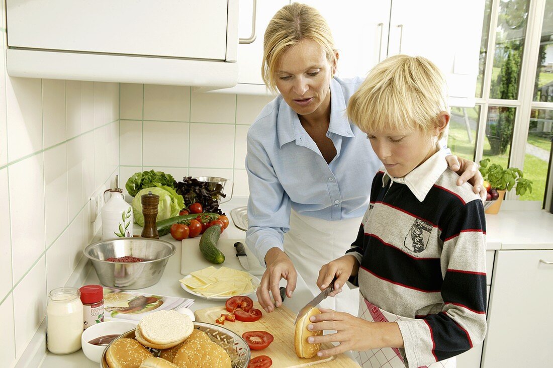 Frau mit blondem Jungen beim Hamburgerbrötchen aufschneiden