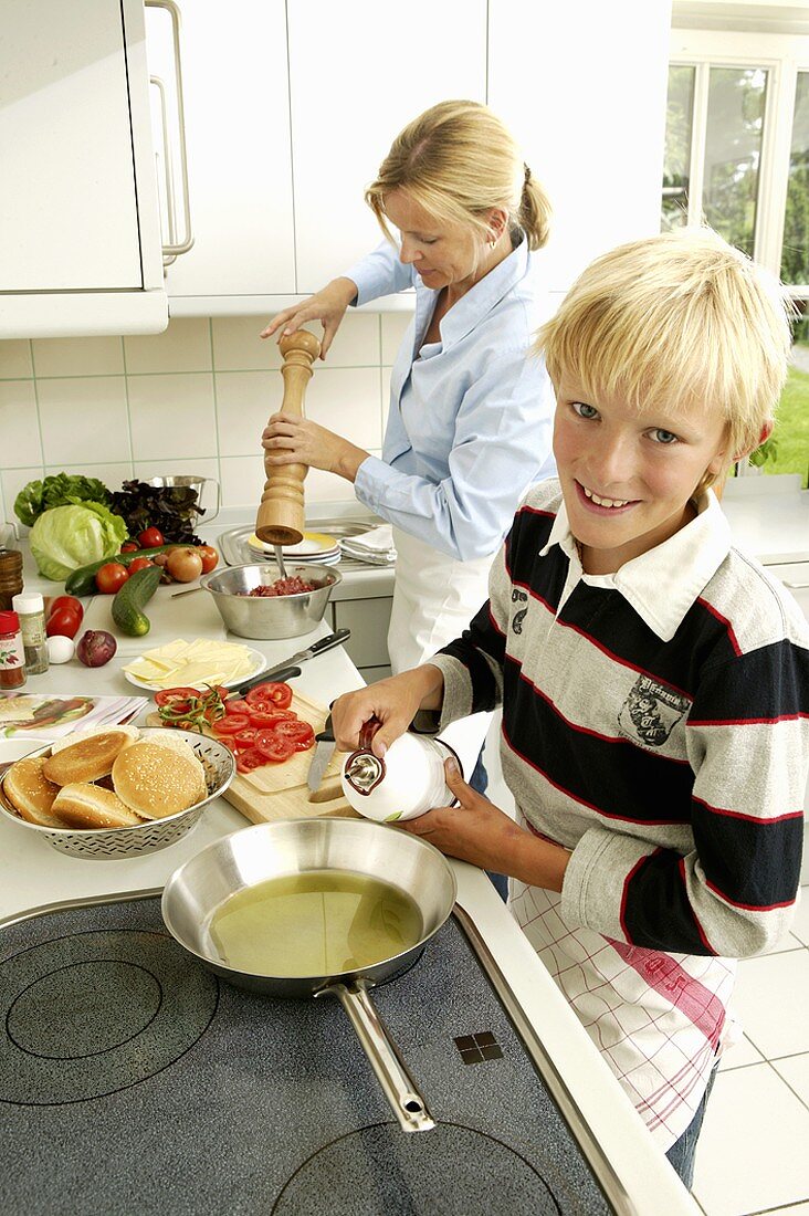 Frau mit blondem Jungen beim Hamburger zubereiten