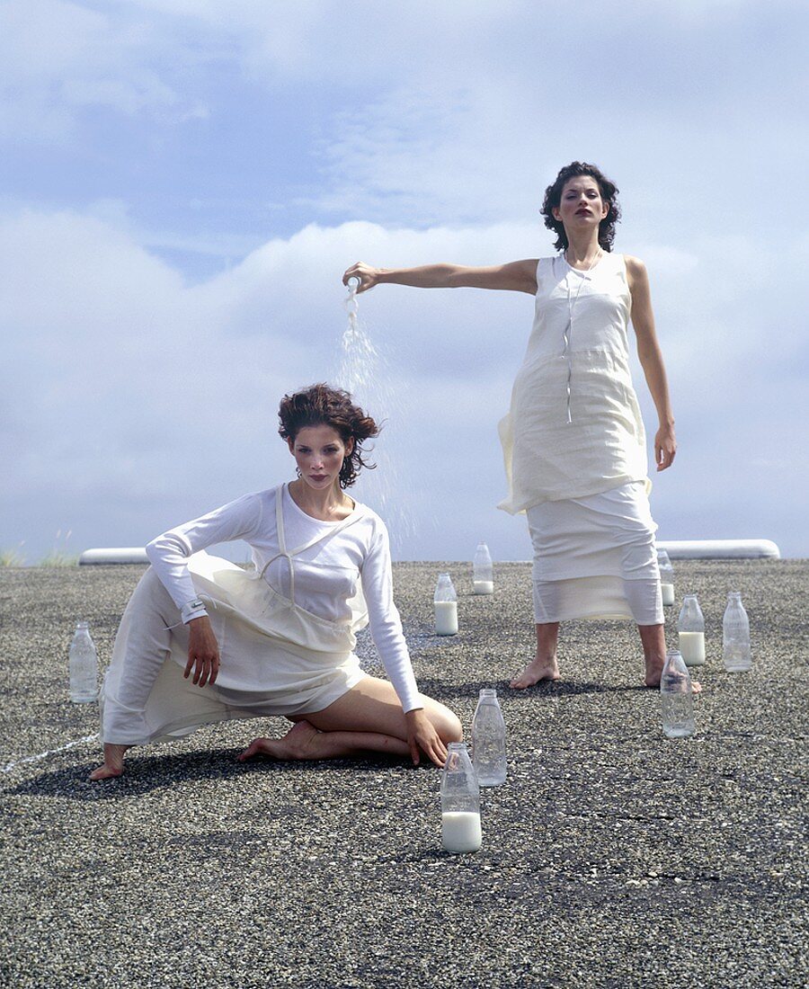 Two women with milk bottles on a roof