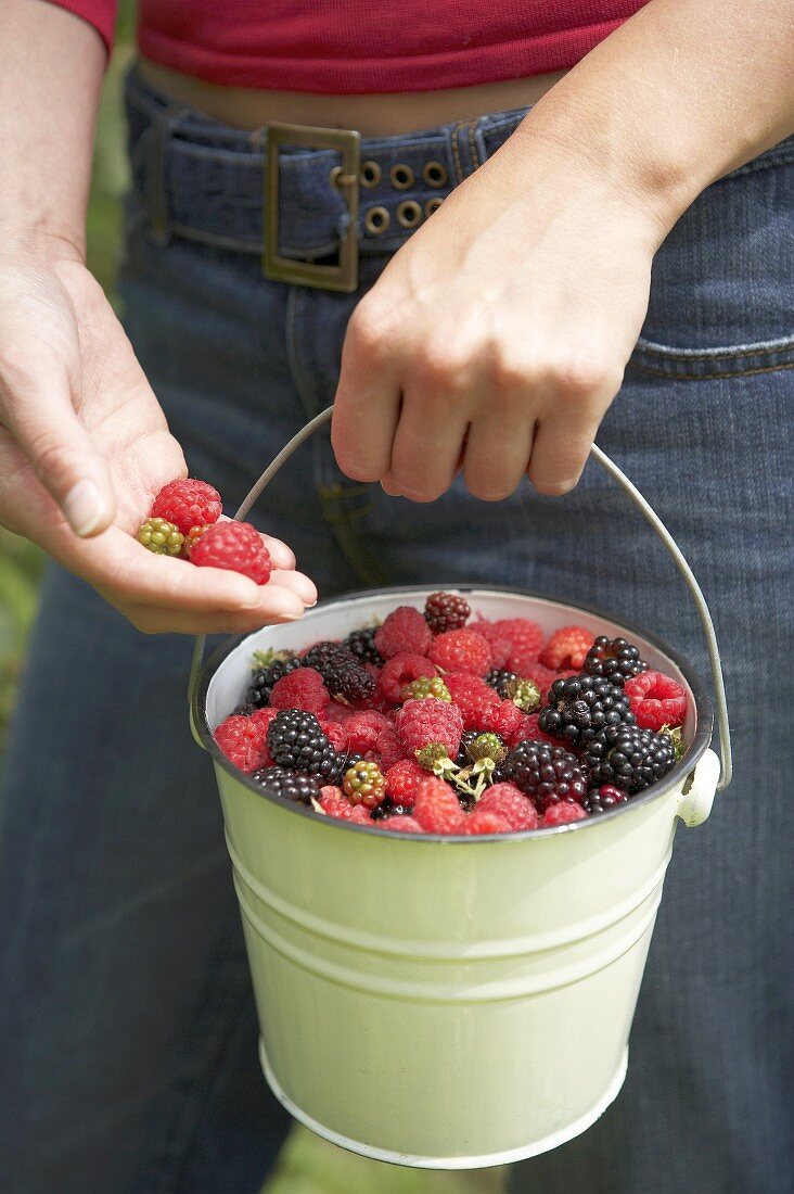 Young woman carrying bucket of freshly picked berries