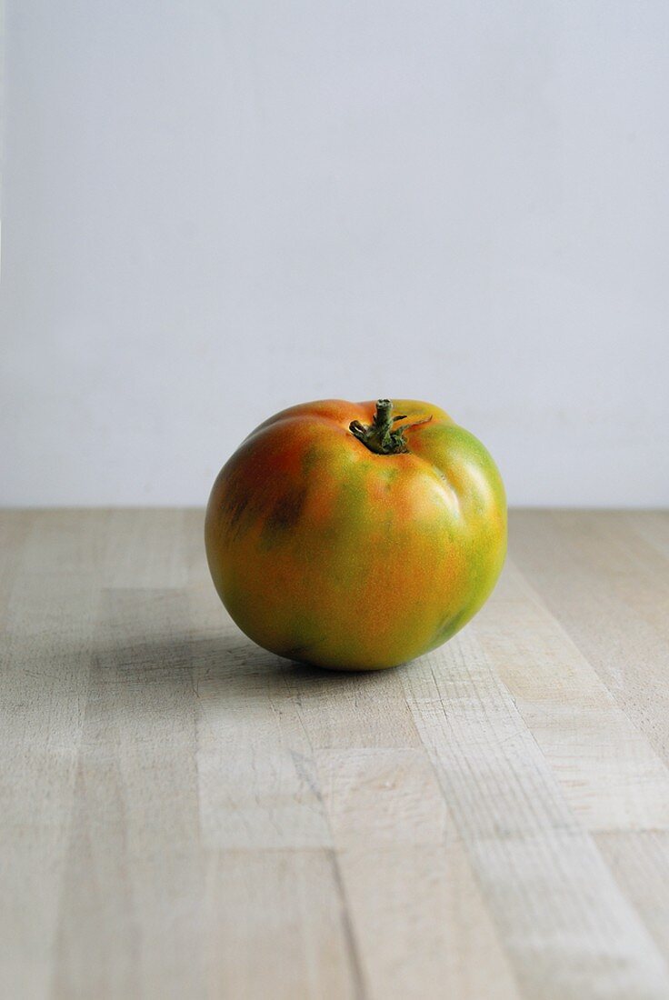 A green tomato on a wooden surface