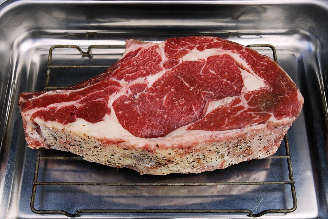 A beef cutlet on a rack in a roasting tin